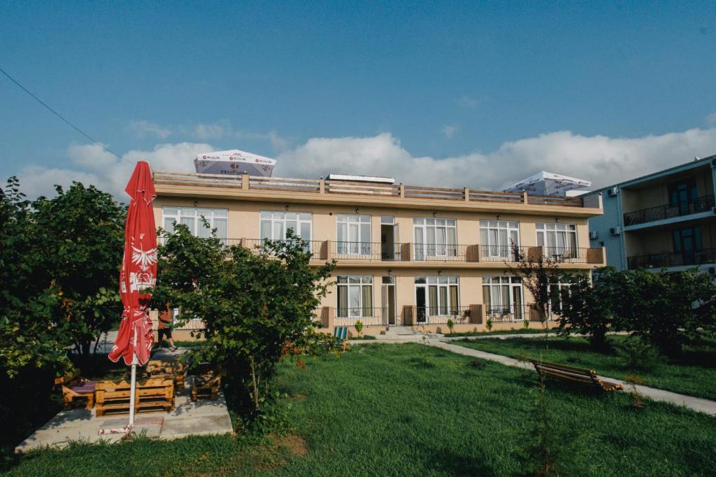 un edificio con un paraguas rojo delante de él en sea-horizon, en Kobuleti