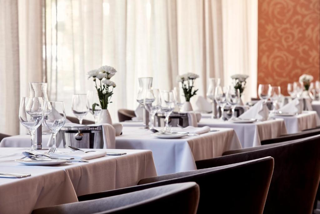 a row of tables with wine glasses and flowers on them at Atlantica Bay - Adults Only in Limassol