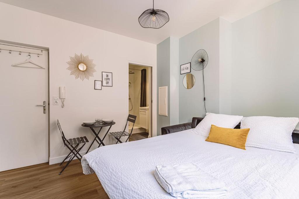 ein weißes Schlafzimmer mit einem weißen Bett und einem gelben Kissen in der Unterkunft Reims - City Center - Cathédrale - FORUM in Reims
