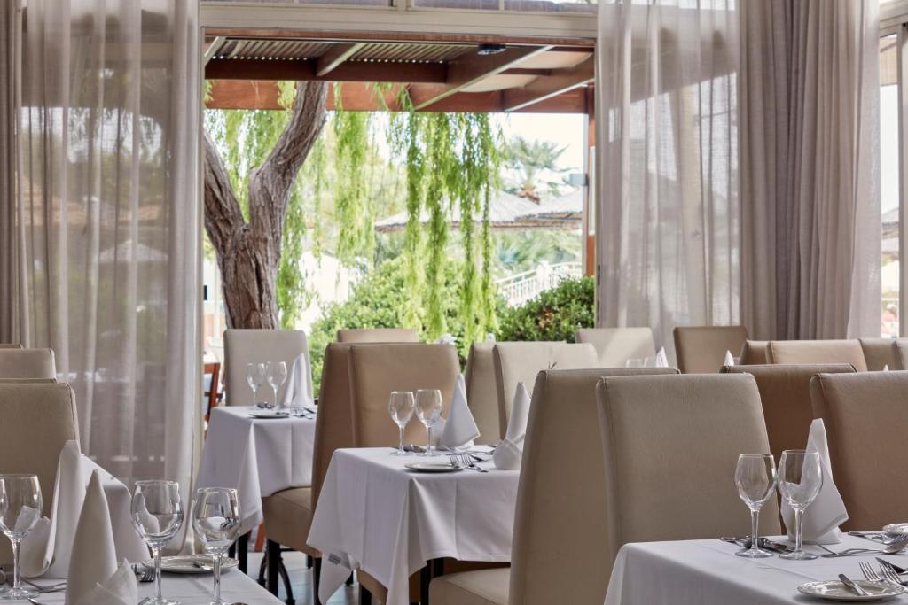 a restaurant with white tables and chairs and a window at Atlantica Bay - Adults Only in Limassol