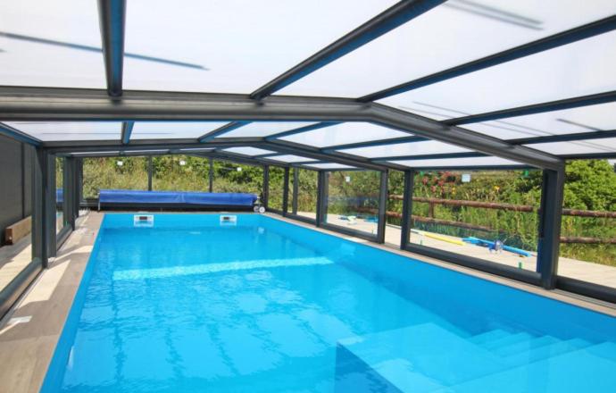 a large swimming pool with an open roof at Gîte De L&#39;Etot Fossey in Marchésieux