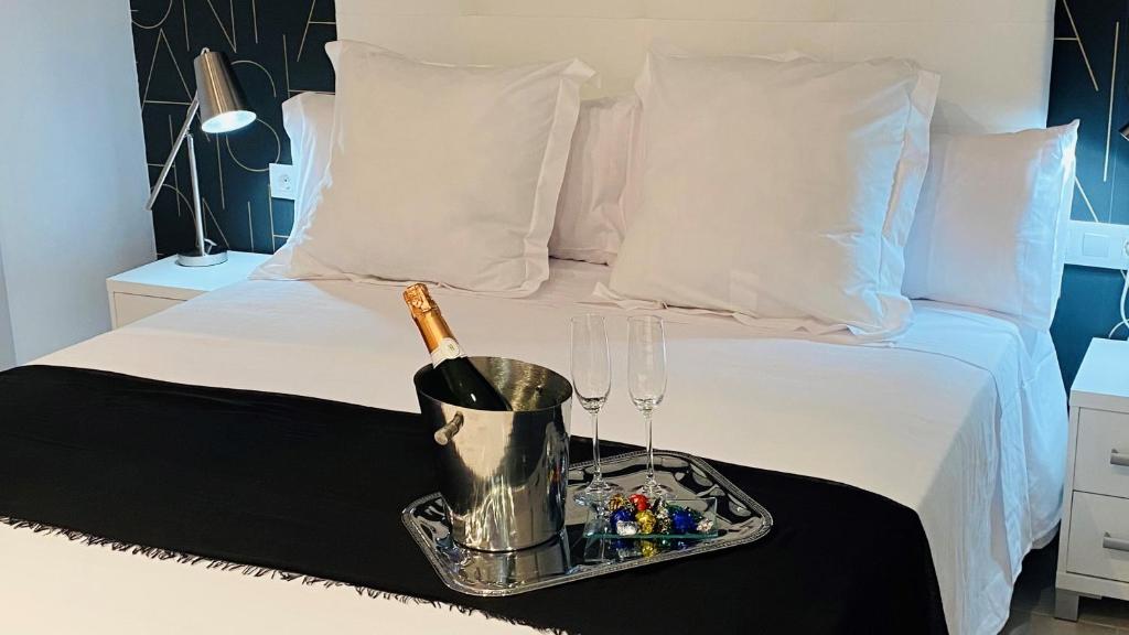 a tray with a bottle of wine and glasses on a bed at Hostal Somnis in Suria