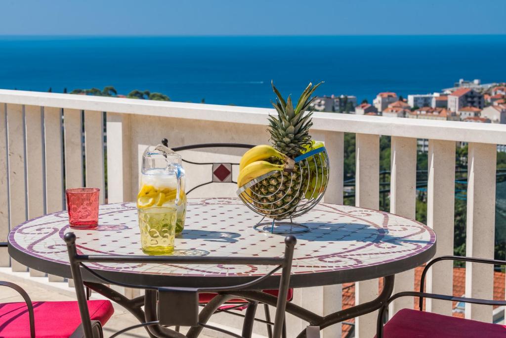 uma mesa com ananás e uma bebida na varanda em Apartment Lea em Dubrovnik