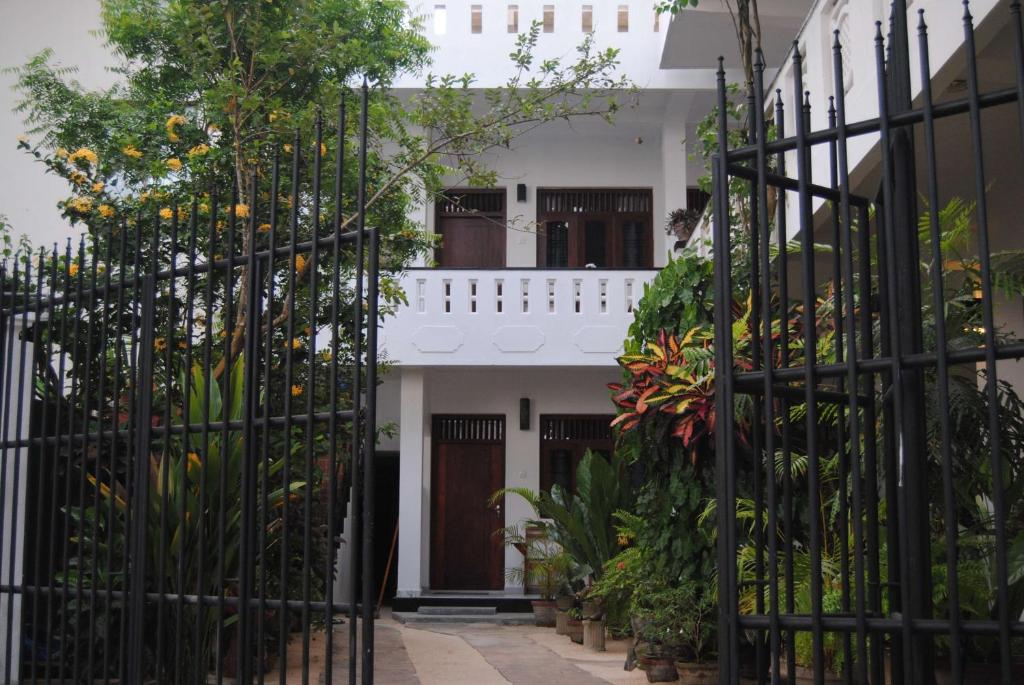 a white building with a gate with plants at Unawatuna Beach Bungalow - in Unawatuna