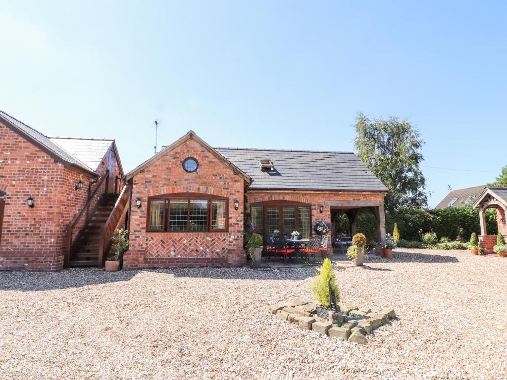 an old brick house with a courtyard in front of it at Honeysuckle Farmhouse in Tarporley