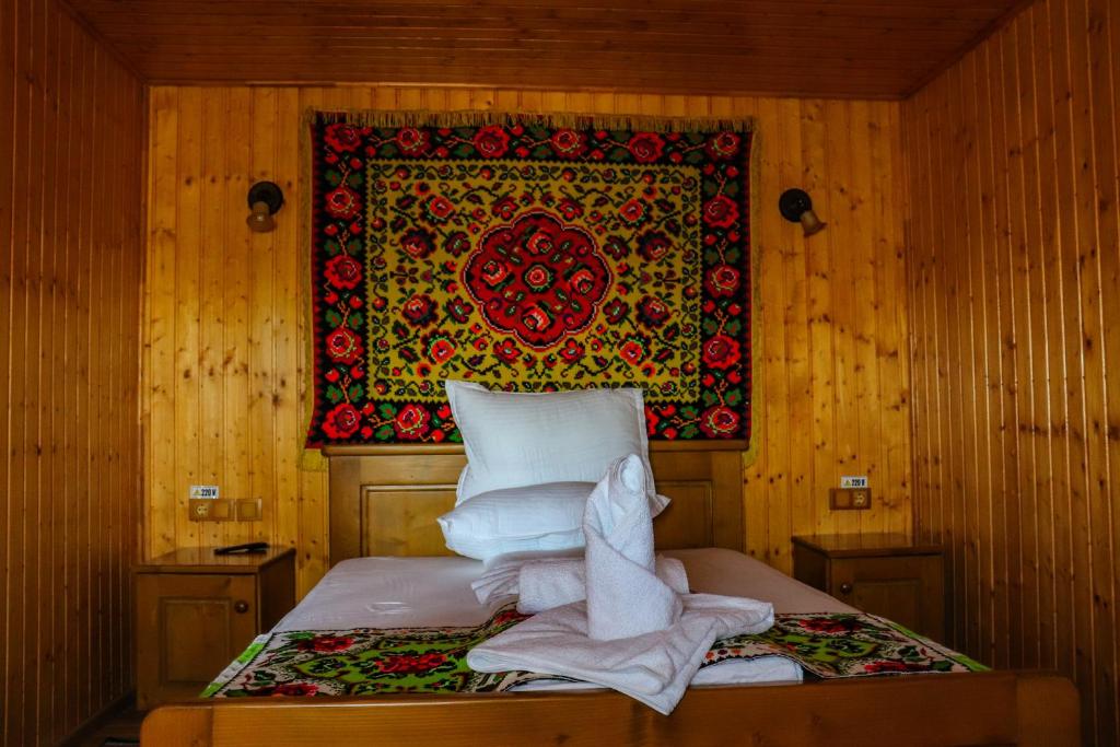 een bed in een kamer met een kleed aan de muur bij Conacul Lupilor in Satu Şugatag