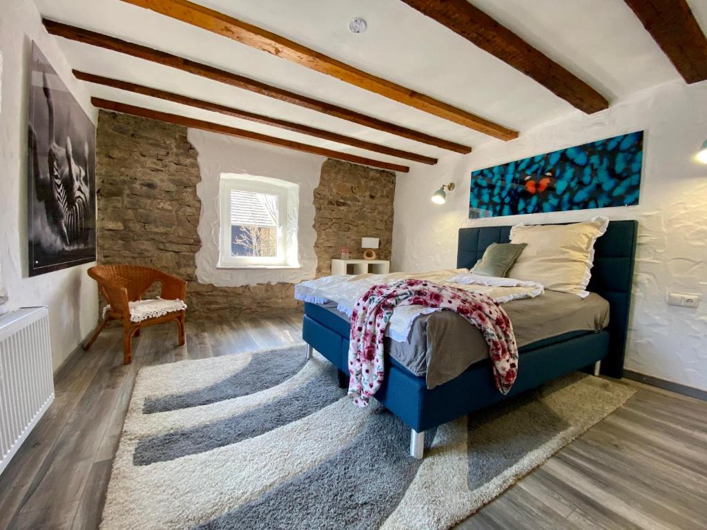 a bedroom with a blue bed and a stone wall at Maisonette Eifel, mit Sauna und Whirlpool in Dahlem