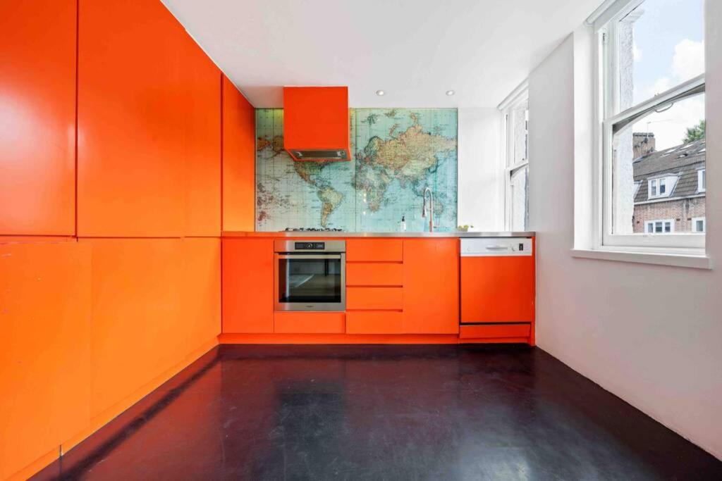 uma cozinha com armários laranja e uma janela em Luxury Apartment in Belsize Park em Londres