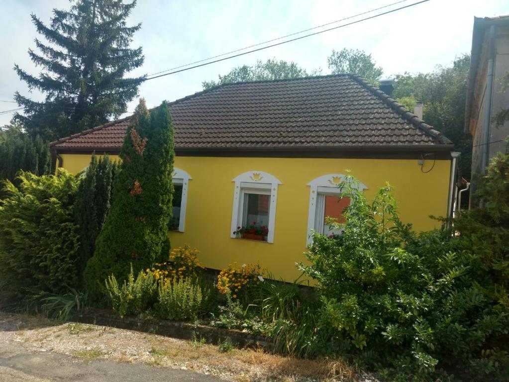 ein gelbes Haus mit schwarzem Dach in der Unterkunft Foki Vendégház in Hidegség