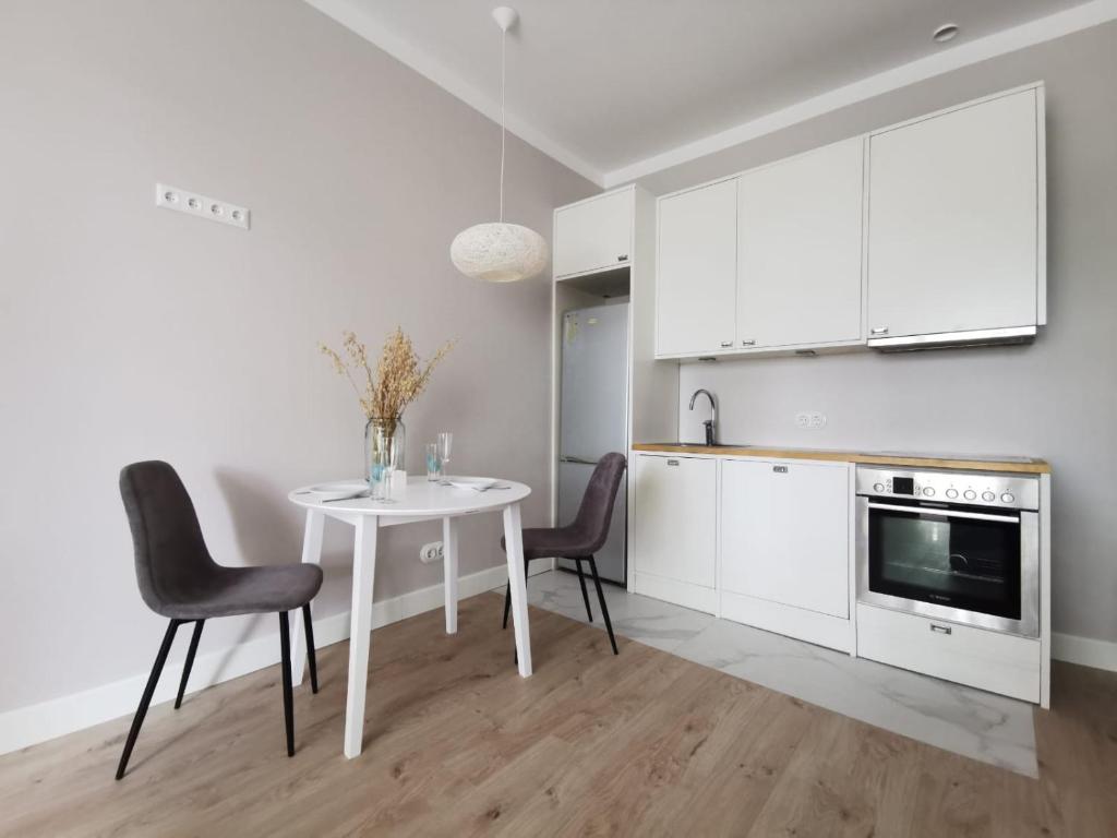 a white kitchen with a white table and chairs at Tolstoi Scandinavian 1 bedroom apartment + free parking in Tartu