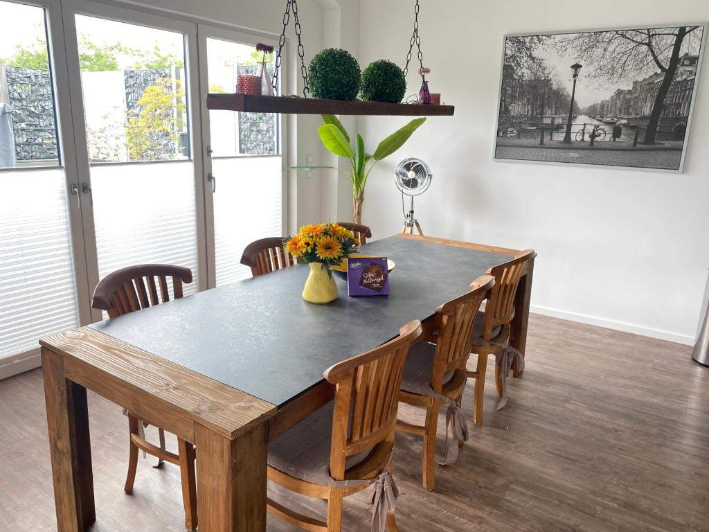 une table à manger avec des chaises et un vase de fleurs dans l'établissement Ferienwohnung Ankerplatz, à Emden