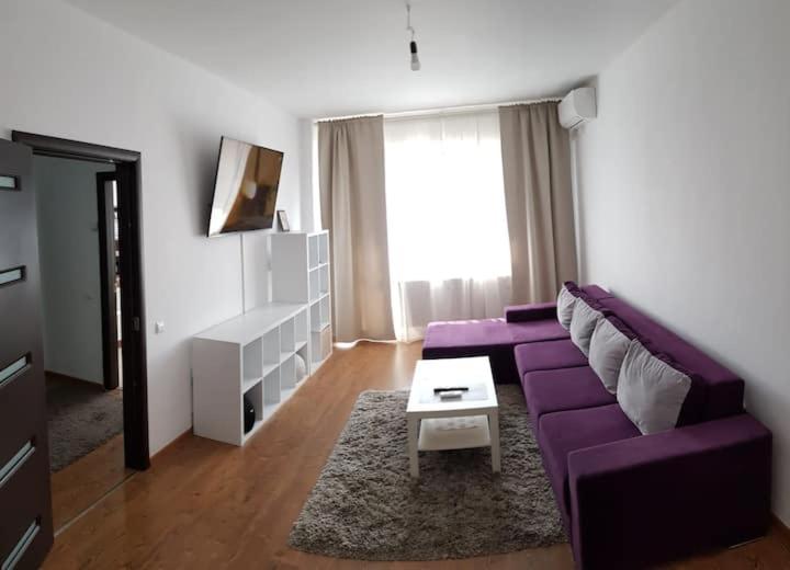 a living room with a purple couch and a table at Cozy Apartment Bucharest in Roşu
