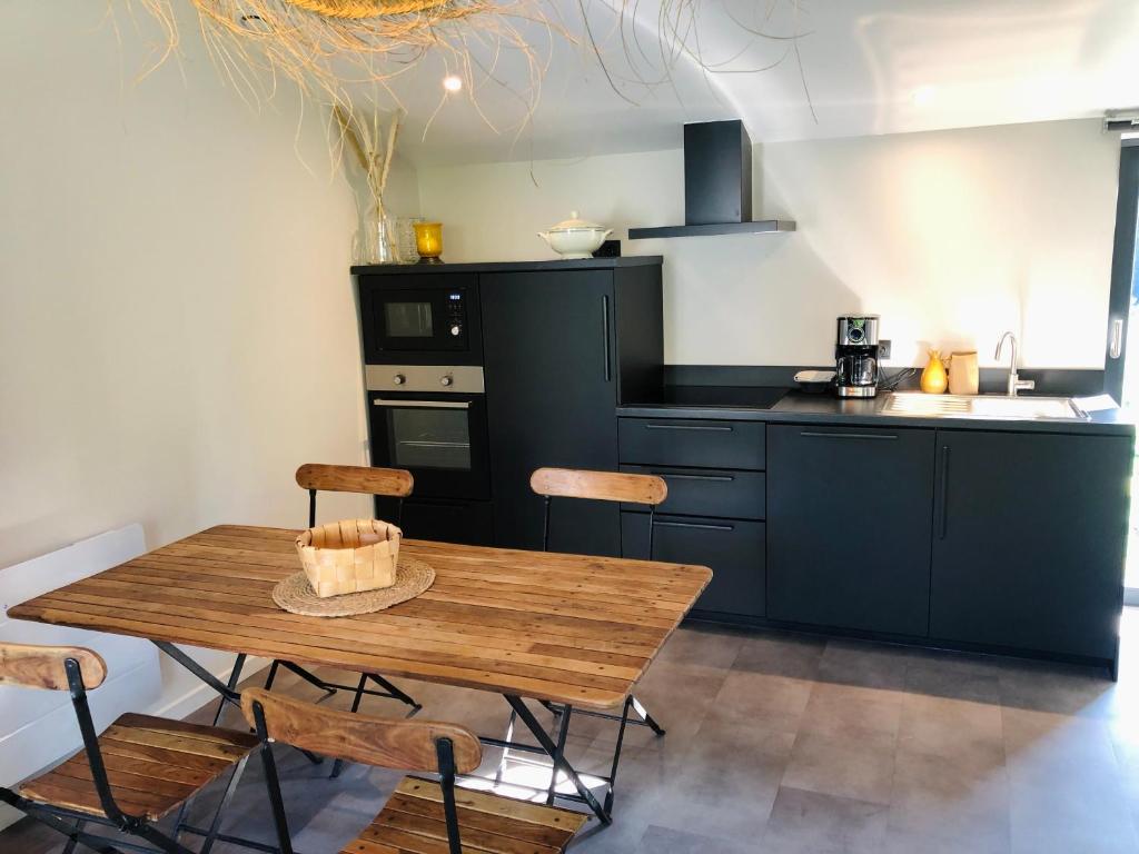 a kitchen with a wooden table and chairs at Appartement Bel Air - Piscine - jacuzzi in Criel-sur-Mer