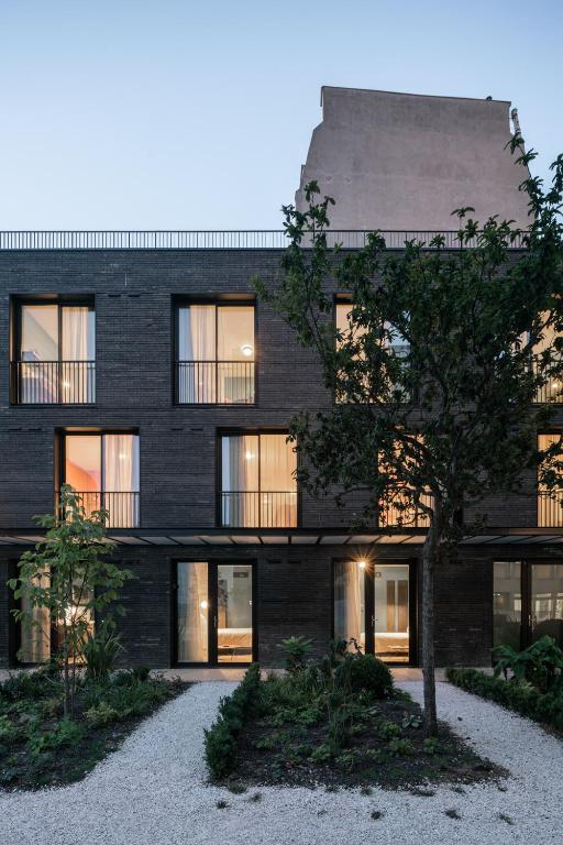 a black brick building with a tree in front of it at Deskopolitan House in Paris