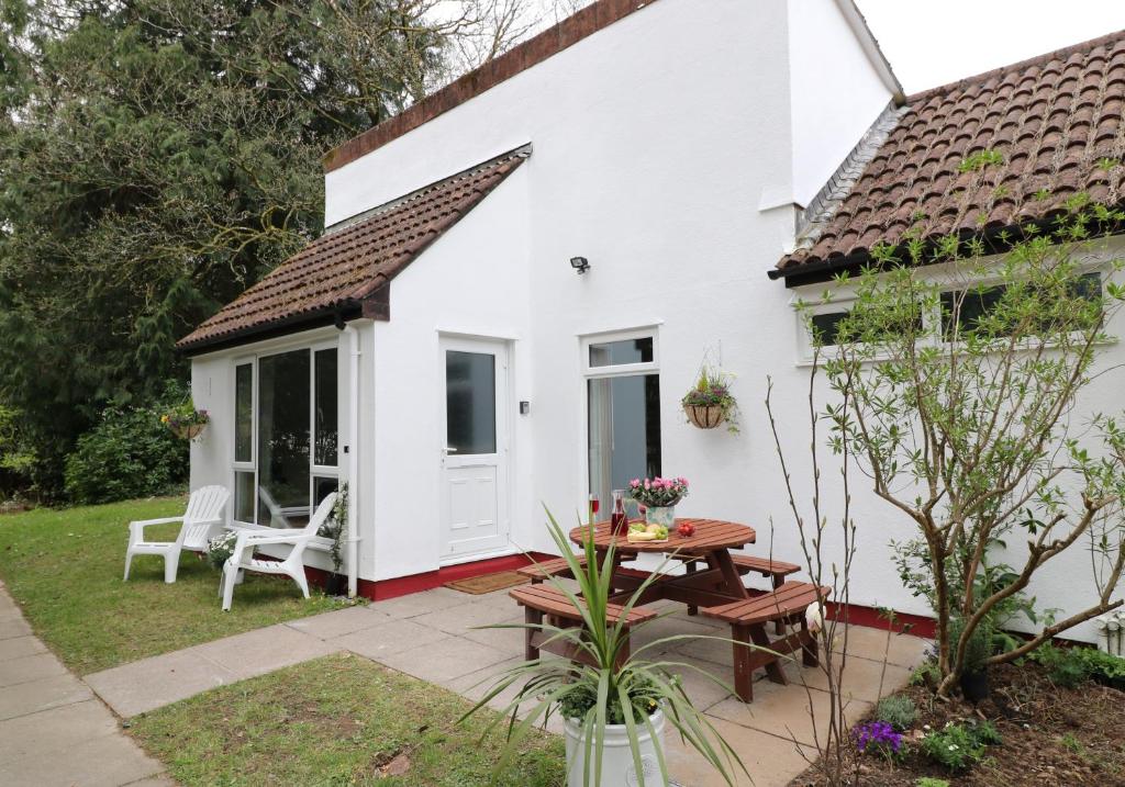 a white cottage with a table and a patio at Manorcombe No1, Callington Cornwall Pool view & prosseco in Callington