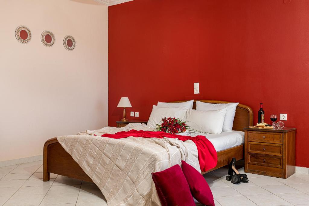 a bedroom with a large bed with a red wall at Dinos Hotel in Tsilivi
