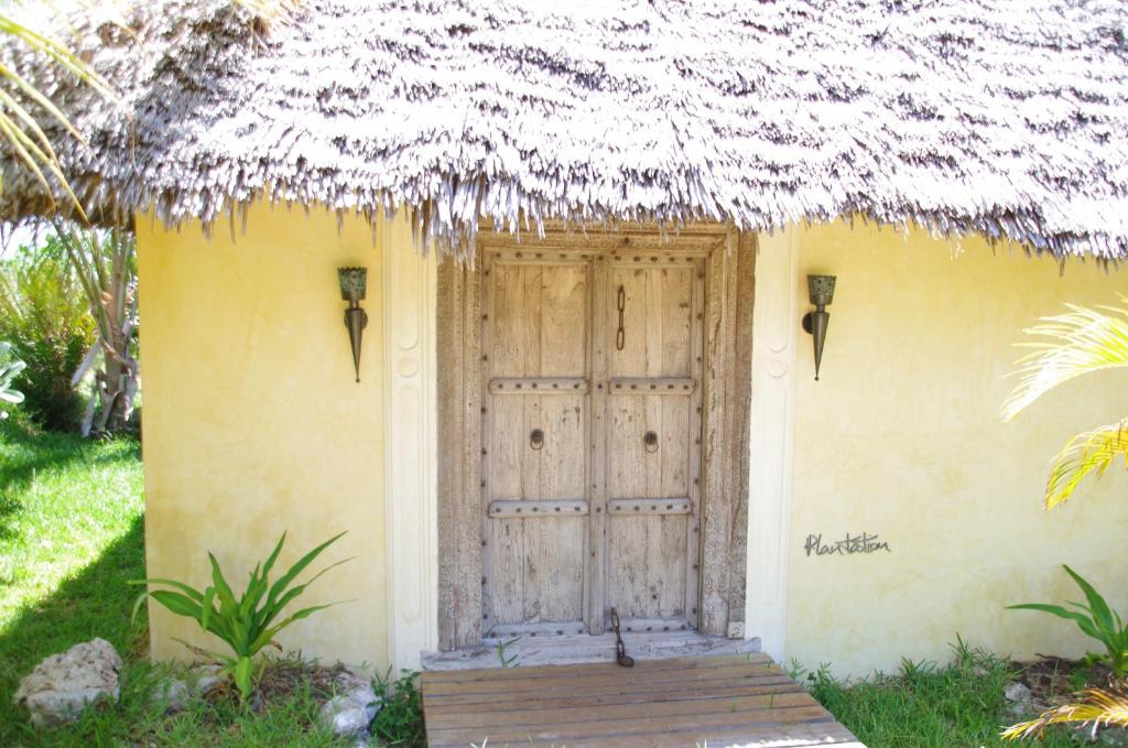 a small yellow house with a door and a grass roof at Qambani Luxury Resort in Michamvi