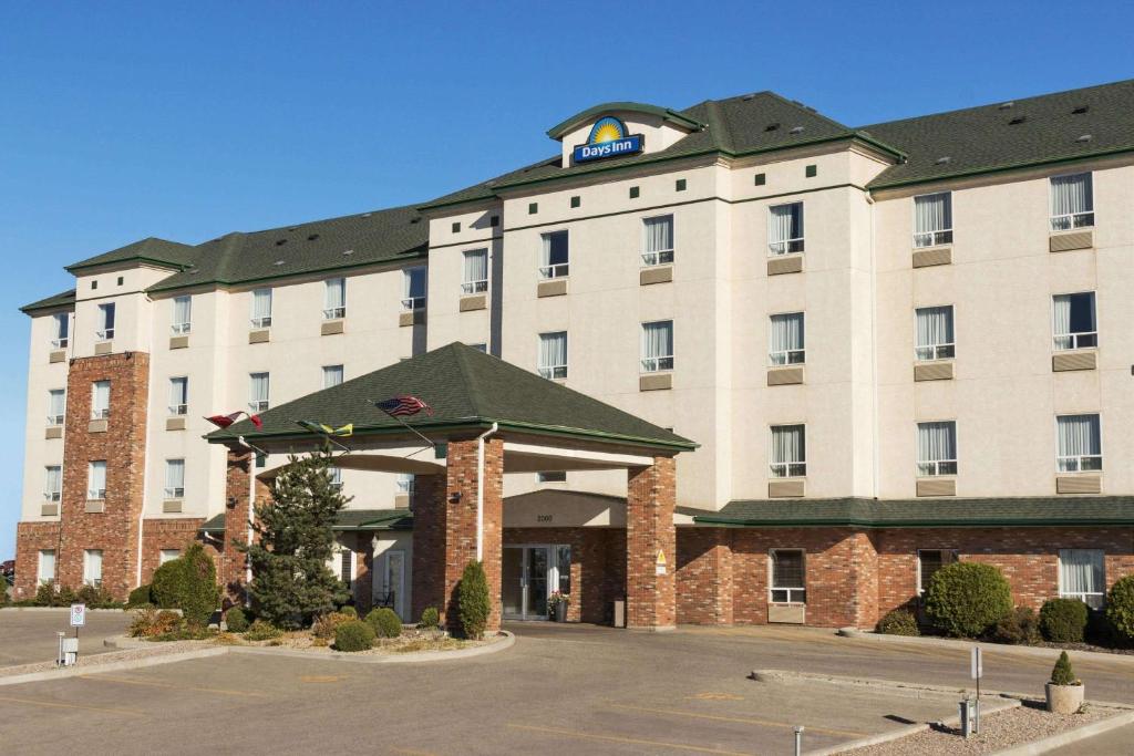 un bâtiment d'hôtel avec un panneau en haut dans l'établissement Days Inn by Wyndham Saskatoon, à Saskatoon