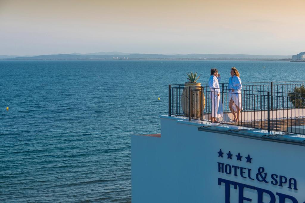ロザスにあるHotel & Spa Terraza 4 Supの二人の女性が水辺を見下ろすバルコニーに立っている