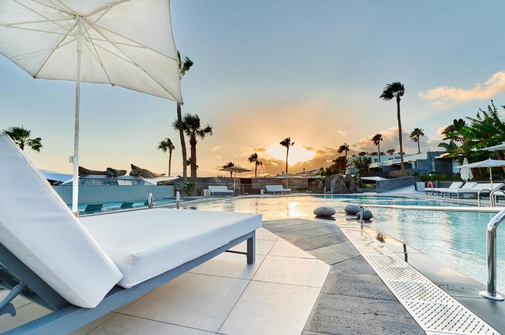 uma piscina com um sofá branco e um guarda-chuva em La Isla y el Mar, Hotel Boutique em Puerto del Carmen