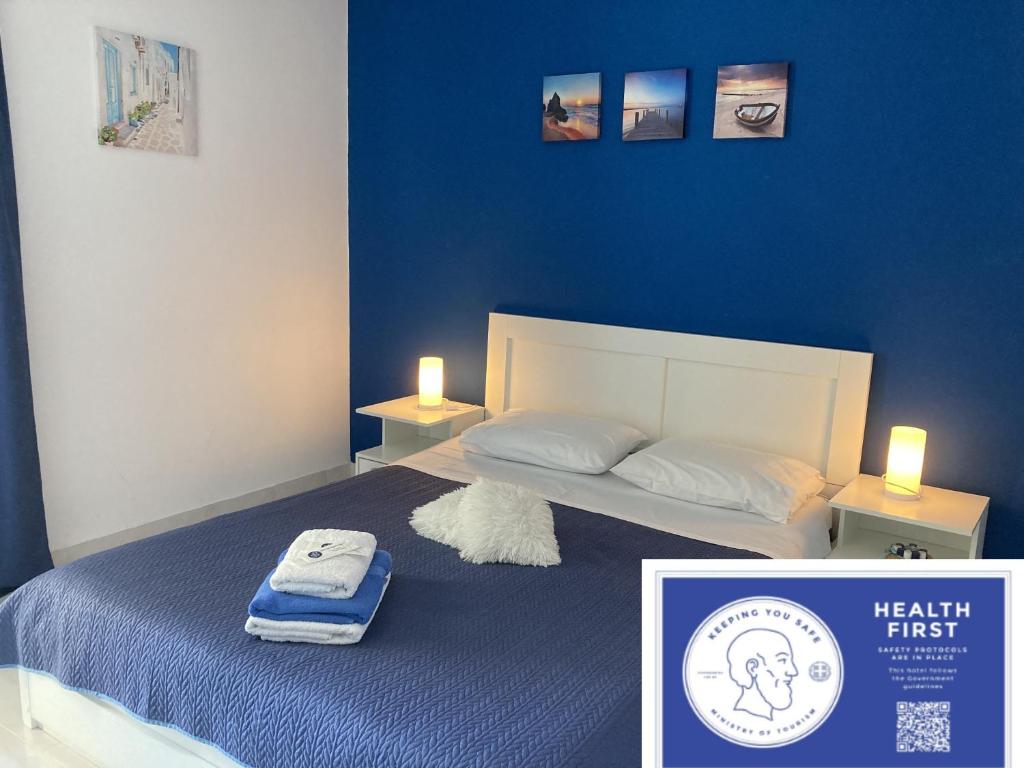 een slaapkamer met een bed met een blauwe muur bij Galotel Agnoudas near the airport in Markopoulon