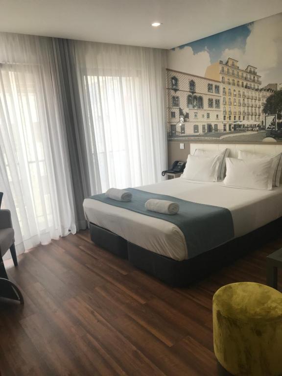 Fenicius Charme Hotel في لشبونة: غرفة نوم بسرير كبير ومخدات بيضاء