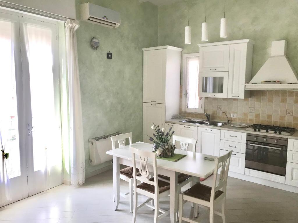 - une cuisine blanche avec une table et des chaises blanches dans l'établissement DELIZIOSA CASA AL CENTRO STORICO DI MARSALA, à Marsala