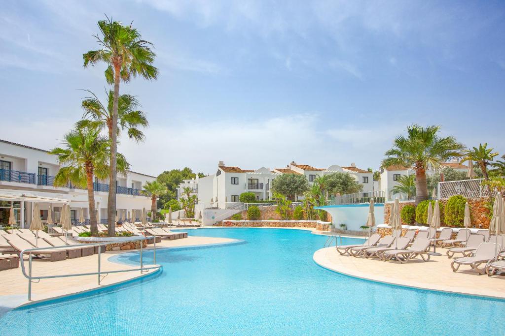 una piscina con tumbonas y palmeras en un complejo en MarSenses Paradise Club, en Cala'n Bosch