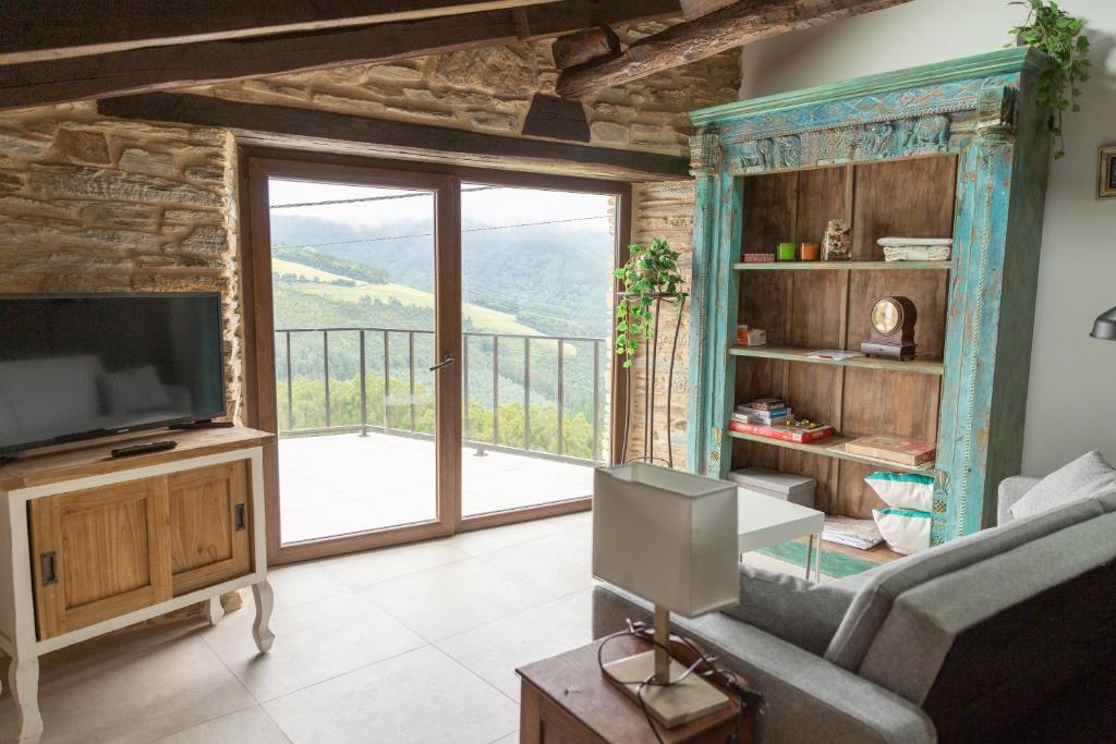 a living room with a television and a balcony at Finca Eiras in Lugo