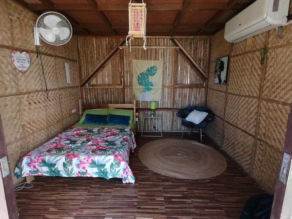 Cette petite chambre comprend un lit et une chaise. dans l'établissement Hilltop Canopy Staycation, à Kinalaglagan