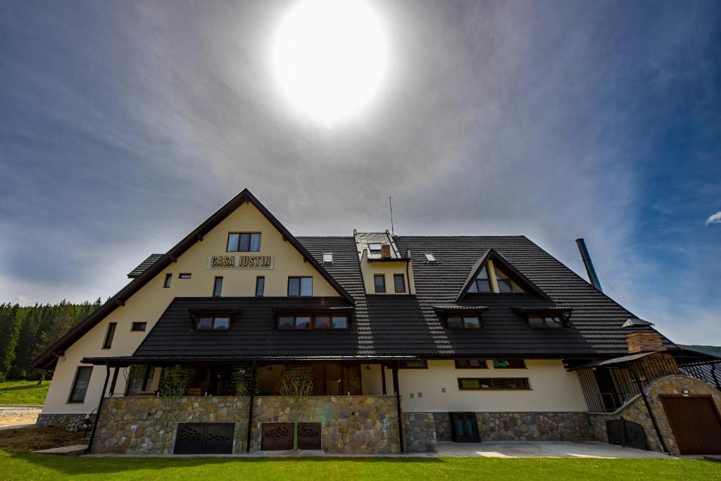 Casa Iustin في مورويني: منزل بسقف أسود مع الشمس في السماء