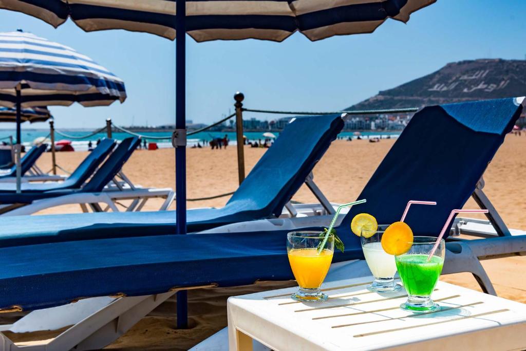 dos bebidas en una mesa con sillas en la playa en Atlantic Hotel Agadir, en Agadir