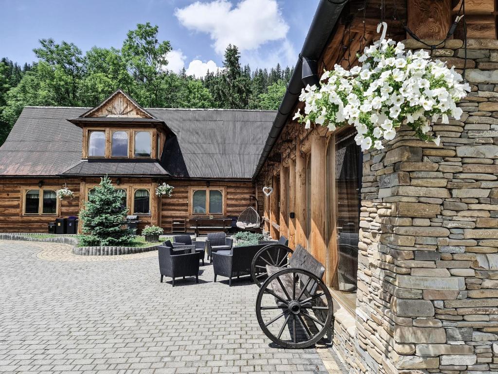 a stone building with a carriage with flowers on it at Apartamenty Góralski DACH NAD GŁOWĄ in Poronin