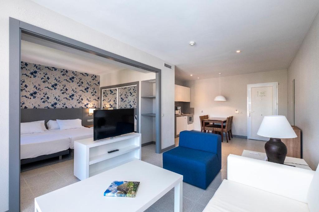 a hotel room with a bed and a blue chair at HG Jardín de Menorca in Son Bou