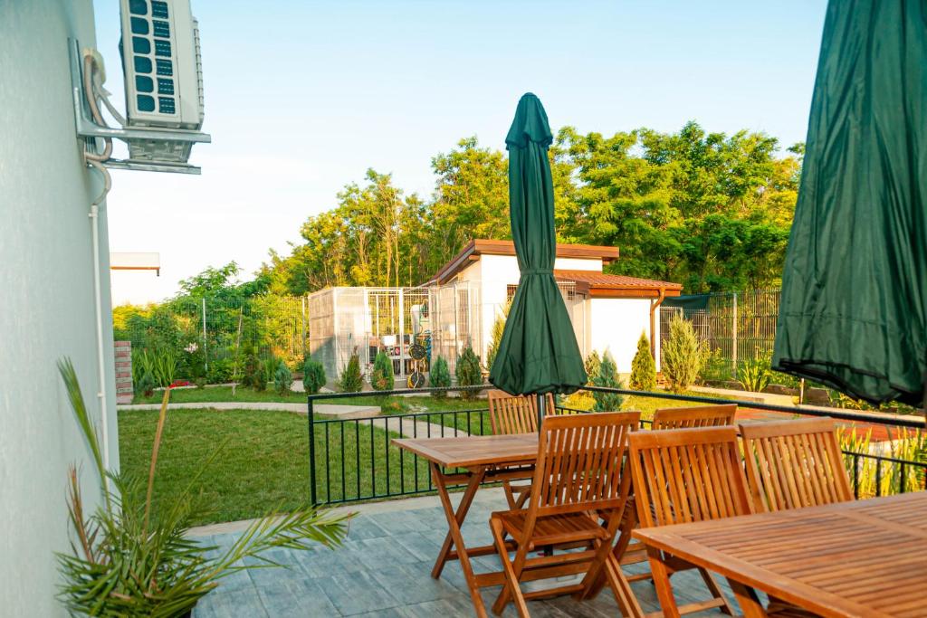 d'une terrasse avec une table et un parasol vert. dans l'établissement PENSIUNEA AGROTURISTICA VALENTINO, à Costinesti