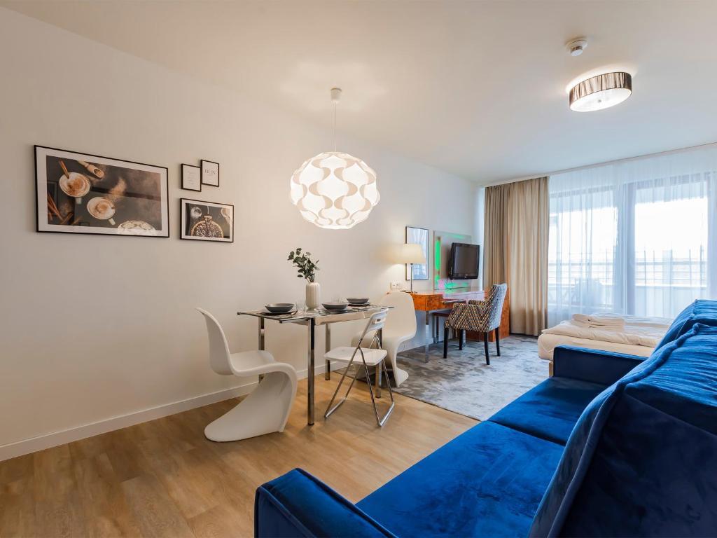 a living room with a blue couch and a table at VacationClub - Sand Hotel Apartment 201 in Kołobrzeg