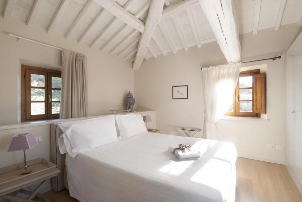a white bedroom with a white bed and a window at Castello Pomino in Borselli