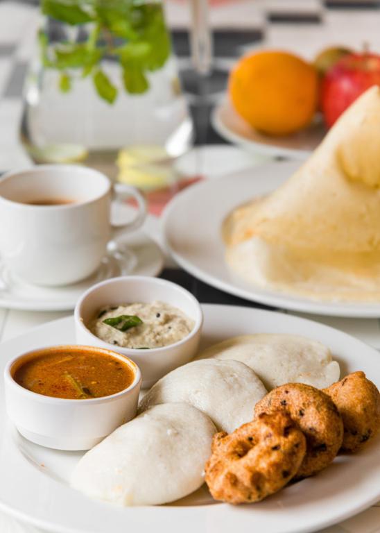 a table with plates of food and cups of soup at Hotel Metropole Inn in Mumbai