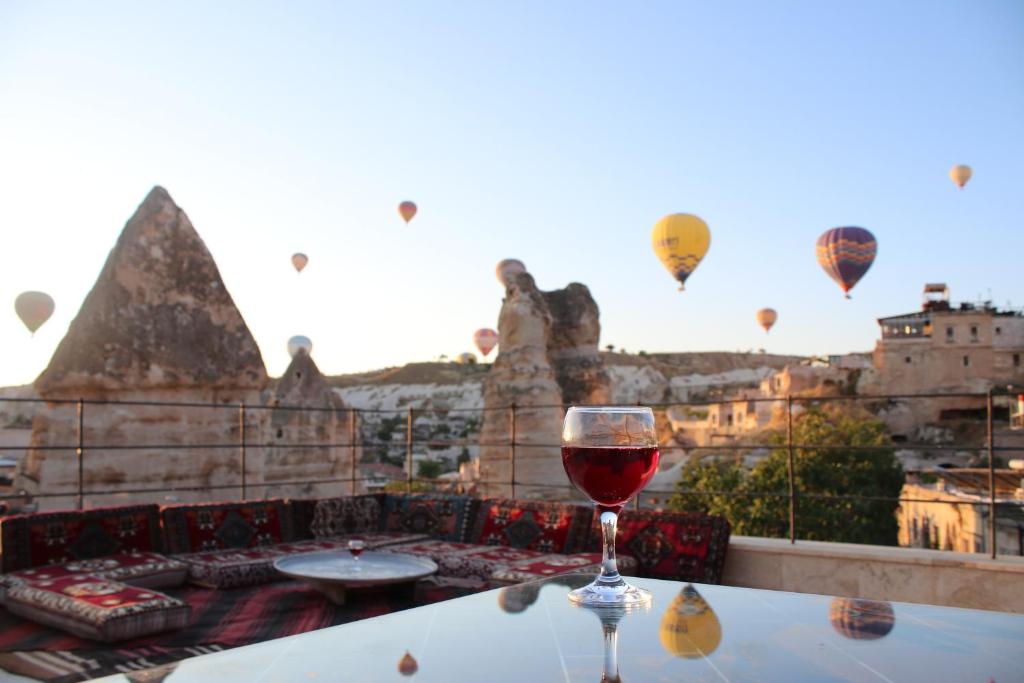 una copa de vino sentada en una mesa con globos de aire caliente en Rose Cave Hotel, en Göreme