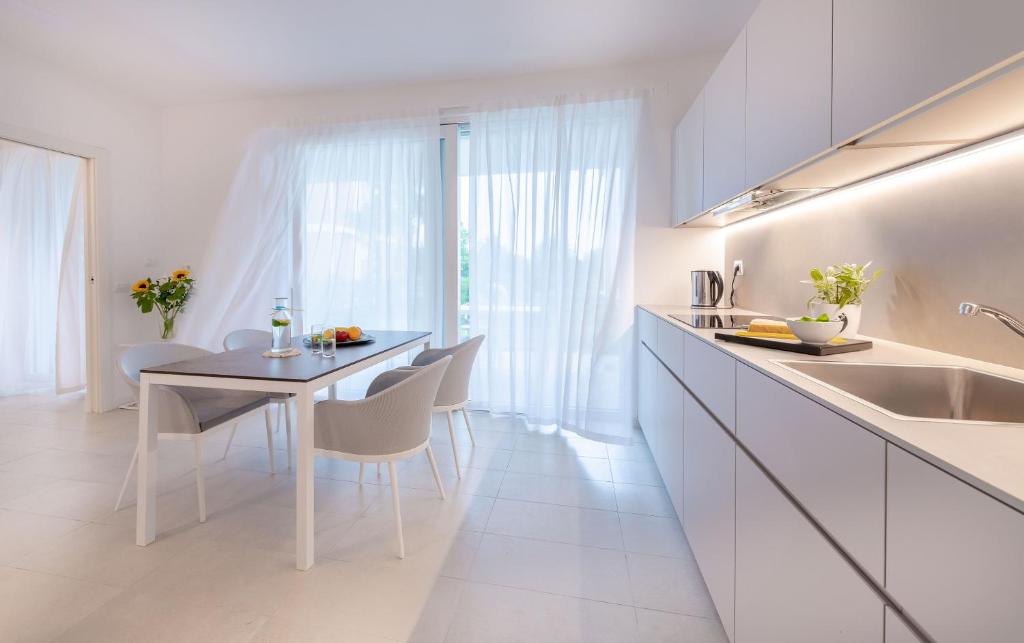 a white kitchen with a dining table and chairs at Pareus Beach Resort in Caorle