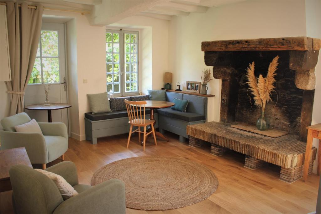 uma sala de estar com lareira e uma mesa e cadeiras em Le Clos des Noues em Hermeray