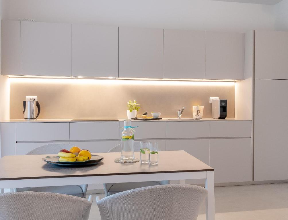 a kitchen with white cabinets and a table with a plate of fruit at Pareus Beach Resort in Caorle