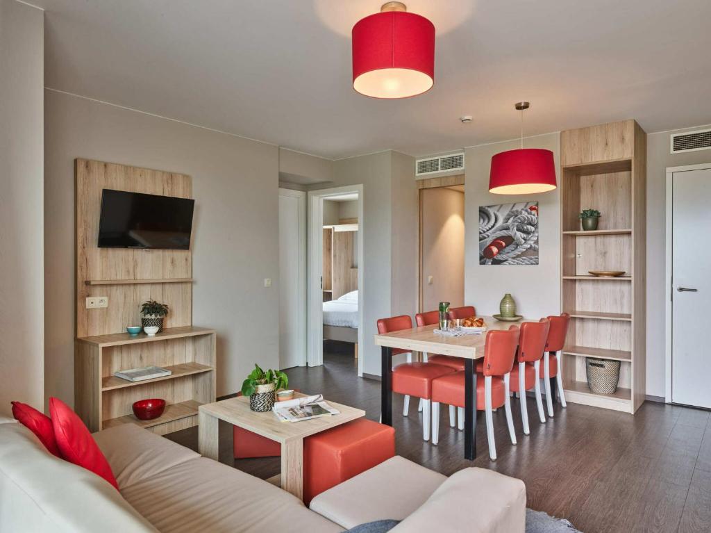 a living room with a couch and a dining room at Holiday Suites Zeebrugge in Zeebrugge