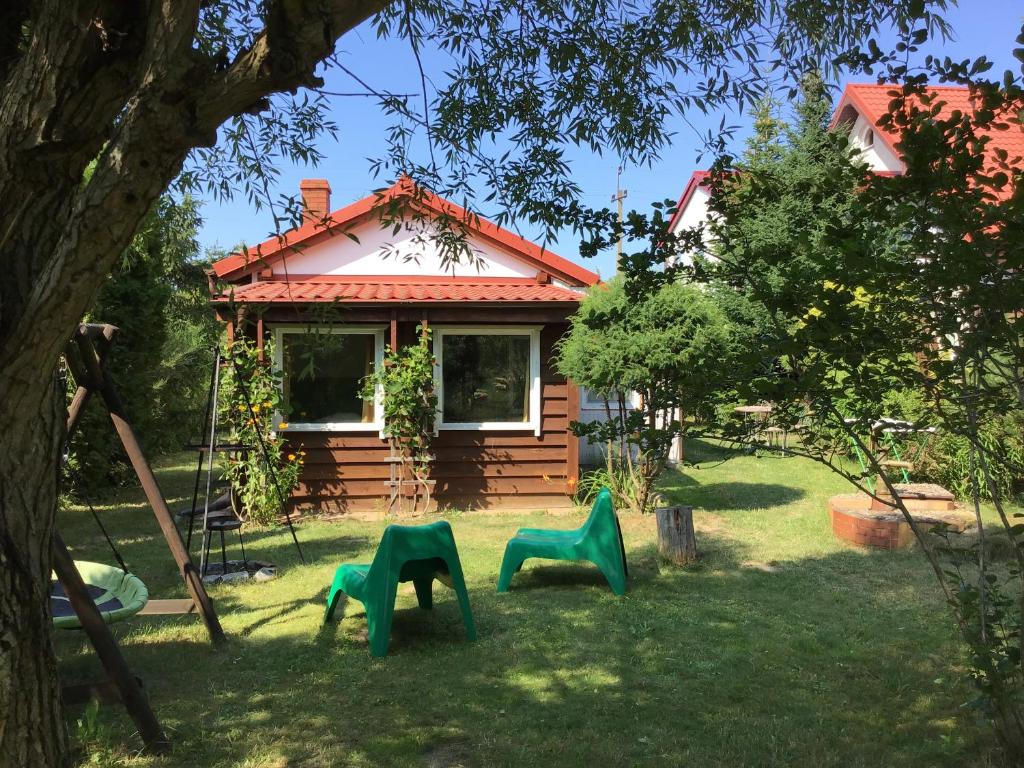 a house with three green chairs in the yard at Siedlisko pod Wierzba in Choczewo