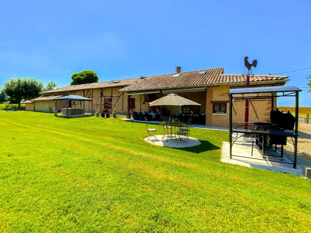 a house with a yard with a picnic table and an umbrella at Ma Longère Bressane in Chaveyriat