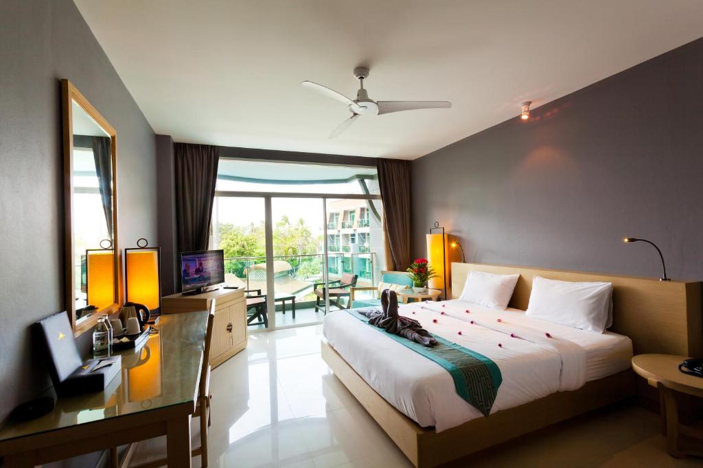 a bedroom with a bed and a desk and a television at Ramaburin Resort Patong - SHA Extra Plus in Patong Beach