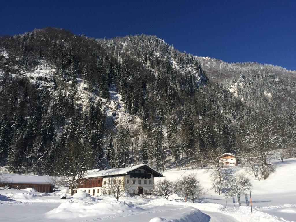 a house in the snow with a mountain at Alpaka-Hof Landinger in Aschau im Chiemgau