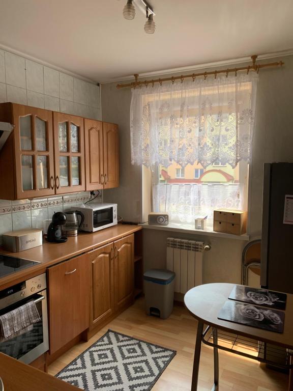 a kitchen with wooden cabinets and a table and a window at Apartament Aria in Ełk