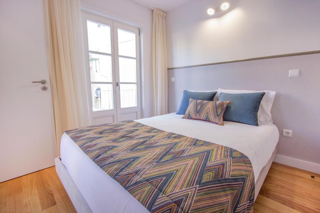 um quarto com uma grande cama branca com almofadas azuis em Santa Luzia Apartments By Guestify em Guimarães