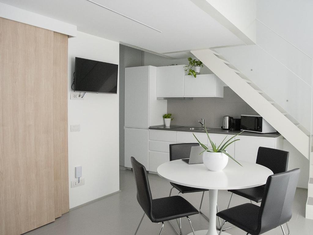 uma sala de jantar branca com uma mesa e cadeiras brancas em Brand new apartments Ortiquattro em Milão